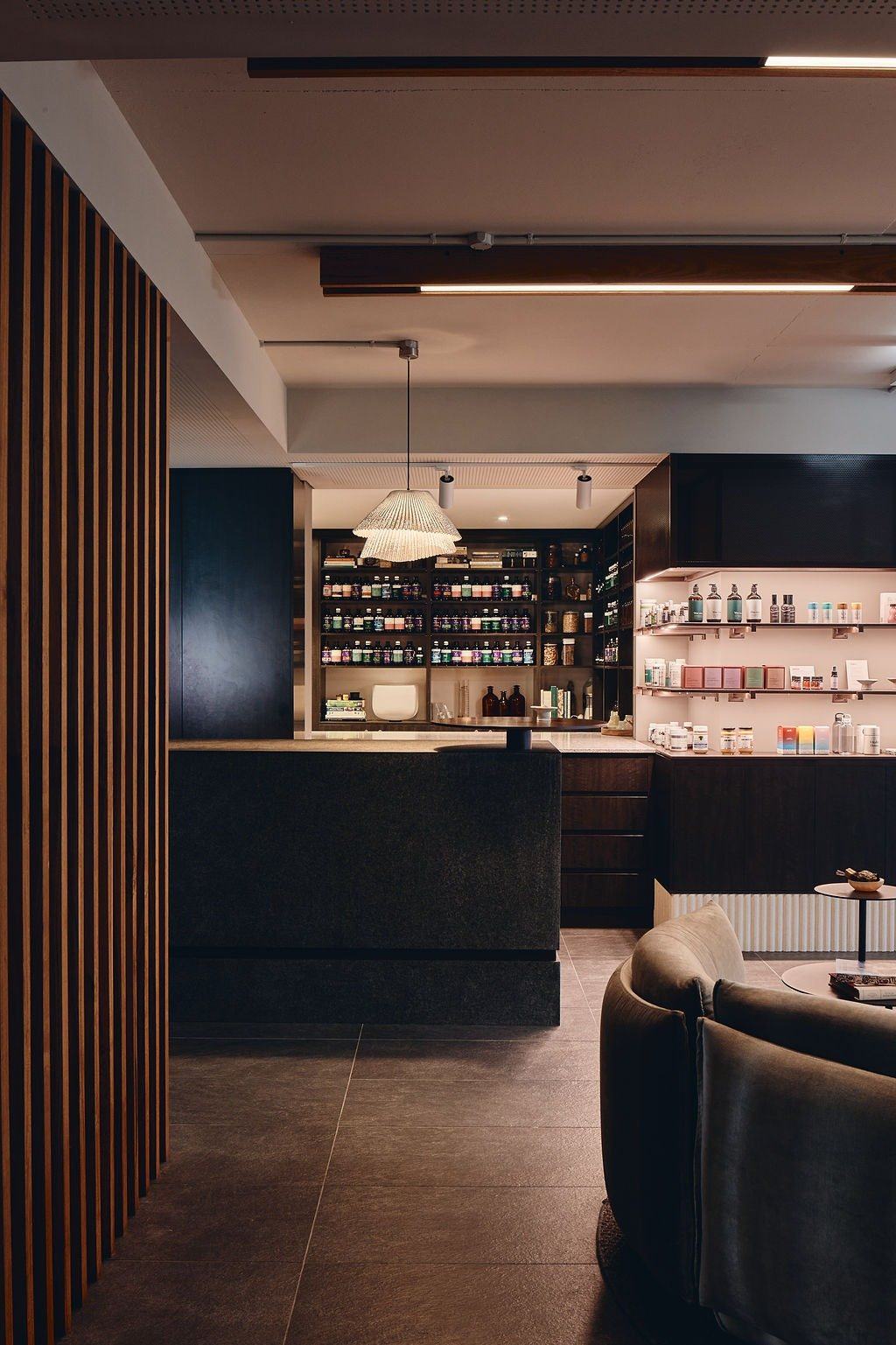 The low-lit reception at Vitality House, with timber battens and dark stone.